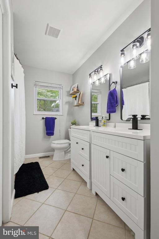 bathroom with visible vents, tile patterned floors, baseboards, vanity, and toilet