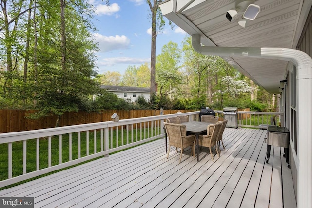 wooden deck featuring ceiling fan, area for grilling, a fenced backyard, outdoor dining area, and a yard