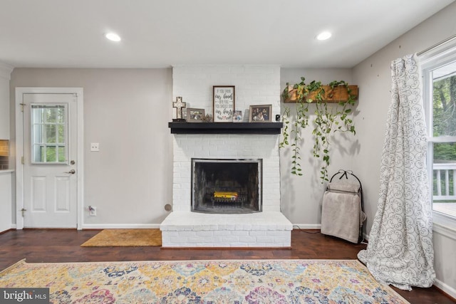 living area featuring baseboards, recessed lighting, a brick fireplace, and wood finished floors
