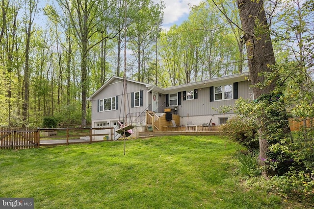 rear view of property featuring a yard, fence, and a garage