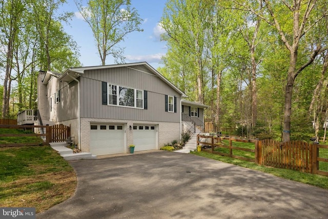view of front of home with fence, stairs, an attached garage, brick siding, and driveway