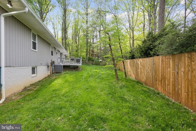 view of yard with fence, central AC unit, and a wooden deck