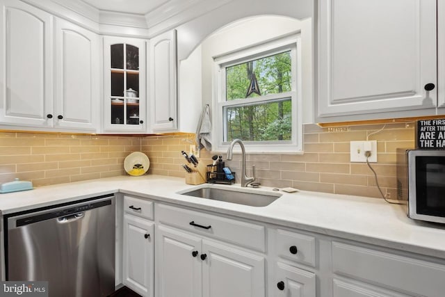 kitchen with stainless steel appliances, white cabinetry, a sink, and glass insert cabinets