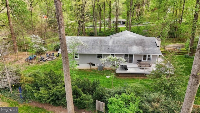 rear view of property with a view of trees, a chimney, central AC, and a deck