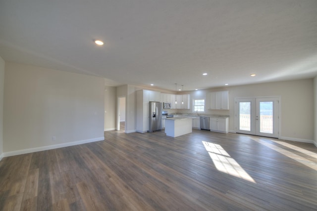 unfurnished living room featuring baseboards, dark wood-style floors, french doors, a sink, and recessed lighting