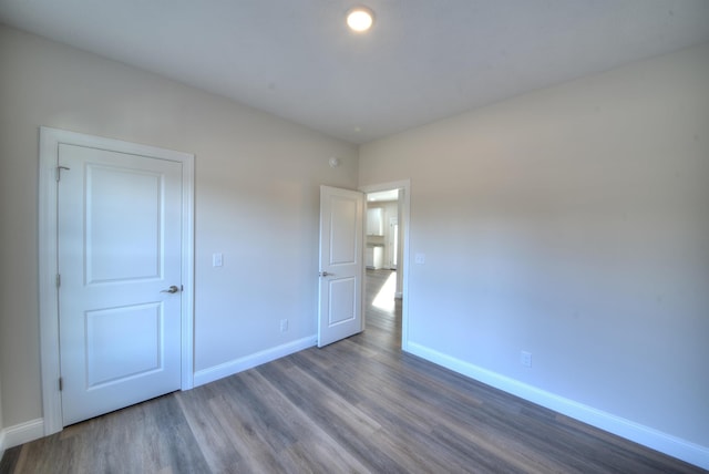 unfurnished bedroom featuring dark wood-style flooring and baseboards