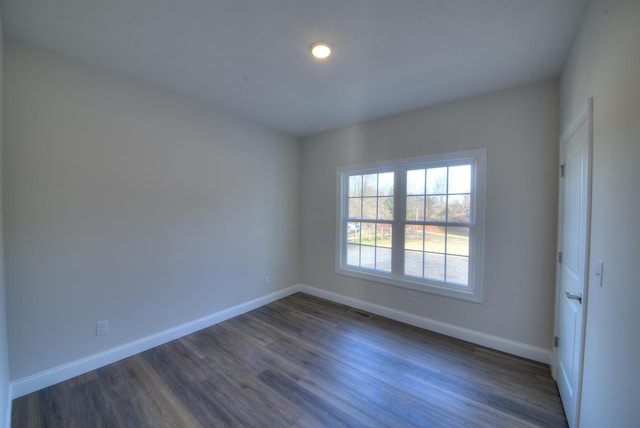 spare room featuring dark wood-style floors, visible vents, and baseboards