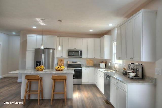 kitchen featuring appliances with stainless steel finishes, a center island, white cabinetry, and a sink