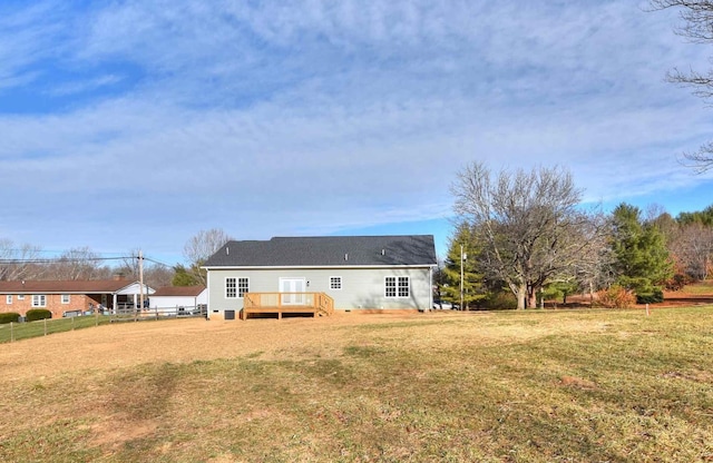 back of property featuring a yard, a wooden deck, and fence