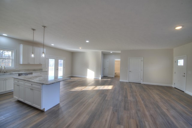 kitchen featuring a sink, white cabinetry, open floor plan, hanging light fixtures, and a center island