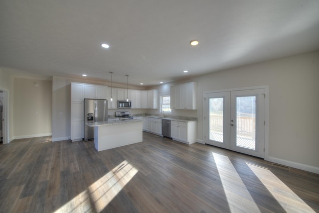 kitchen with stainless steel appliances, white cabinets, french doors, a center island, and pendant lighting