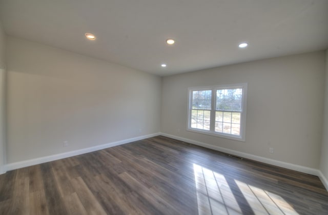 spare room with baseboards, dark wood-style flooring, and recessed lighting