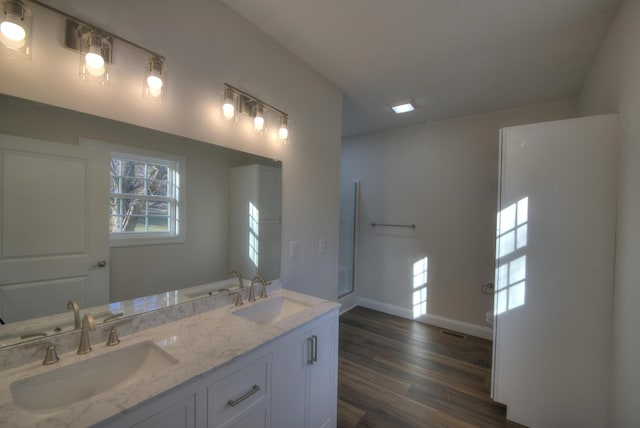 bathroom featuring double vanity, a sink, baseboards, and wood finished floors