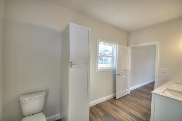 bathroom with toilet, wood finished floors, vanity, and baseboards