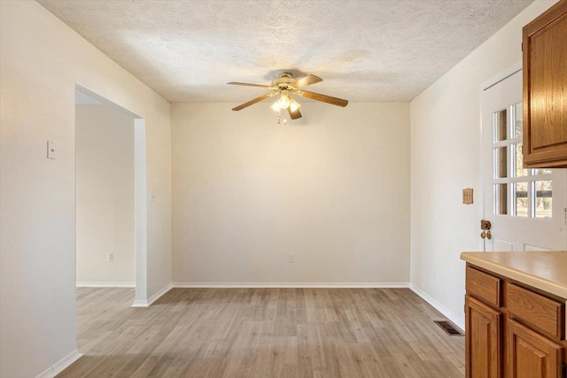 interior space featuring ceiling fan, a textured ceiling, and light hardwood / wood-style flooring