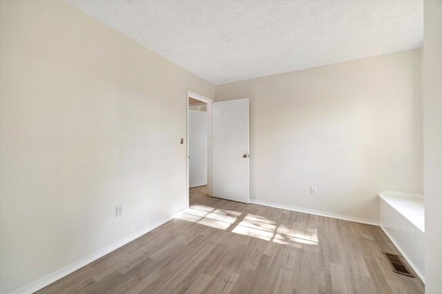 spare room with light hardwood / wood-style floors and a textured ceiling