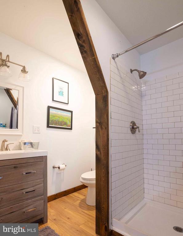 bathroom featuring toilet, wood finished floors, vanity, baseboards, and a shower stall