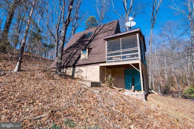 rear view of house featuring a sunroom and a shingled roof