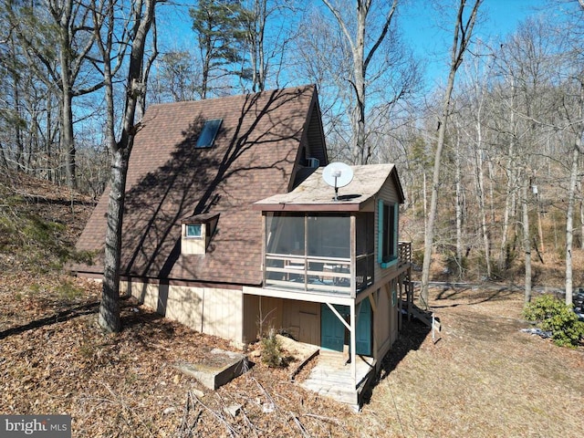 view of side of home featuring a sunroom and roof with shingles