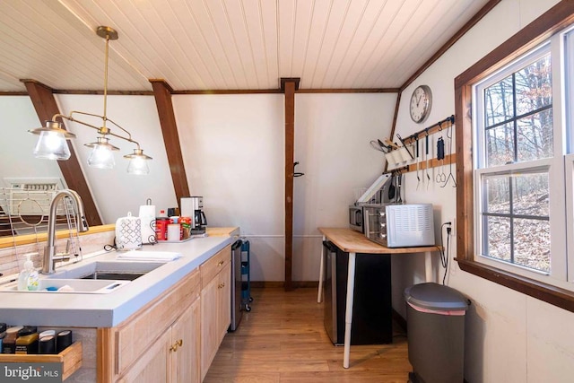 kitchen with light brown cabinets, a sink, a healthy amount of sunlight, light countertops, and hanging light fixtures