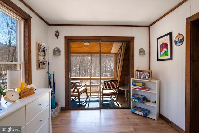 interior space featuring baseboards, crown molding, and light wood finished floors