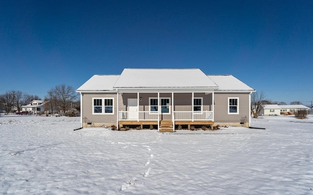 snow covered back of property with a porch