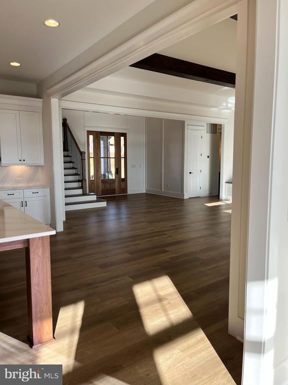 unfurnished living room featuring dark wood-style floors, recessed lighting, beam ceiling, and stairs