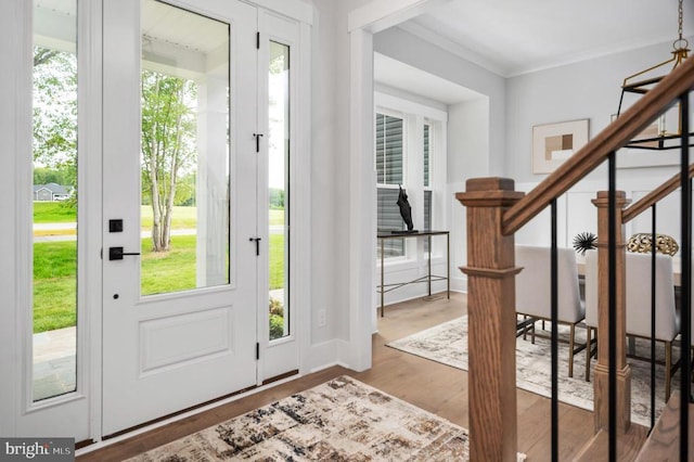 entryway featuring ornamental molding, a healthy amount of sunlight, stairway, and wood finished floors