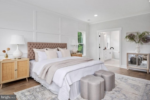 bedroom with crown molding, recessed lighting, wood finished floors, and a decorative wall