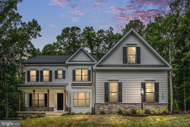 view of front facade with covered porch, board and batten siding, a standing seam roof, metal roof, and stone siding