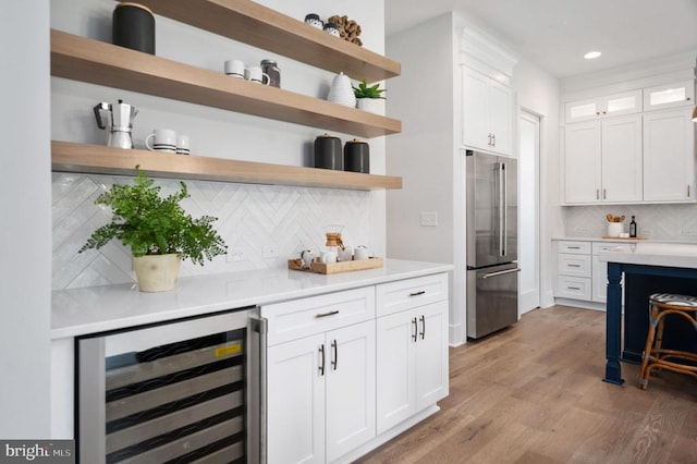 bar with high end refrigerator, wine cooler, light wood-type flooring, backsplash, and recessed lighting