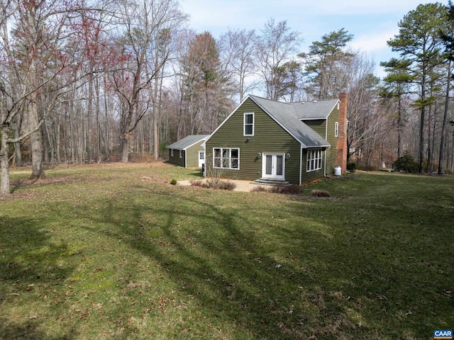 view of side of property featuring a chimney and a yard