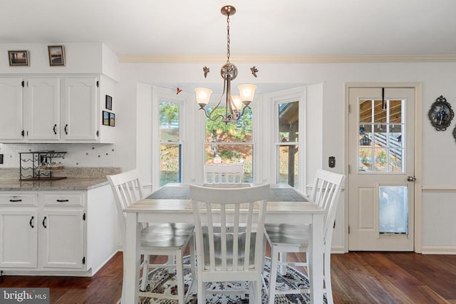 dining space featuring dark wood-type flooring, crown molding, and a chandelier