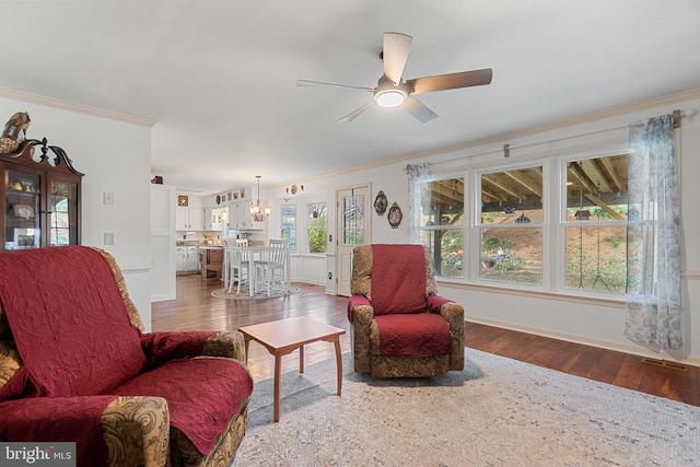 living room featuring hardwood / wood-style floors, ceiling fan with notable chandelier, and ornamental molding