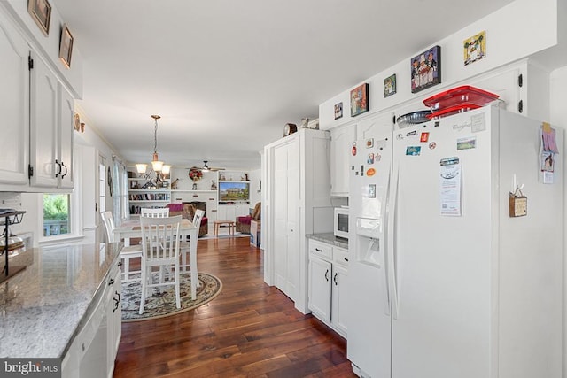 kitchen featuring hanging light fixtures, dark hardwood / wood-style floors, white appliances, light stone countertops, and white cabinets