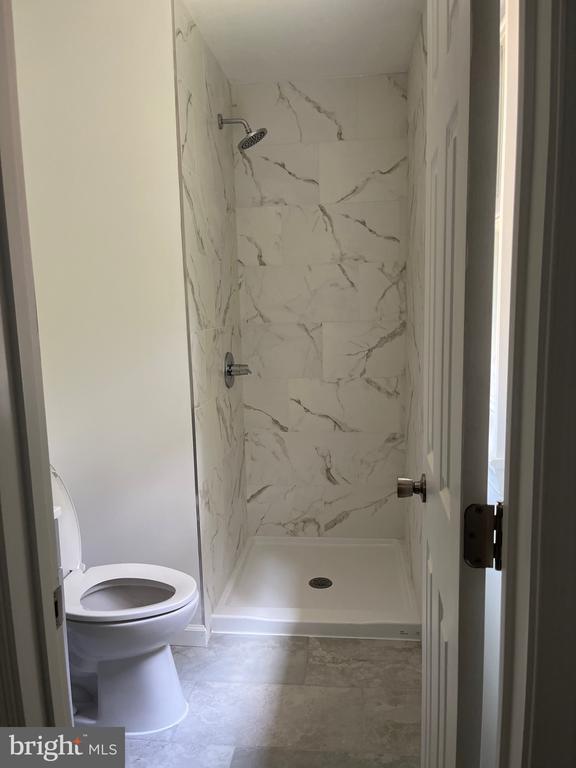 bathroom with a tile shower and toilet