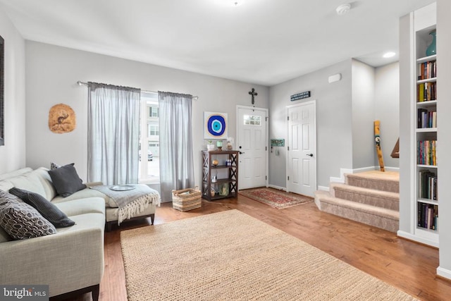 living area with wood finished floors, baseboards, and stairs