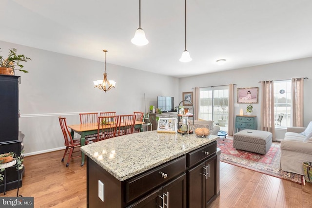 kitchen with pendant lighting, a kitchen island, light wood-style floors, open floor plan, and an inviting chandelier