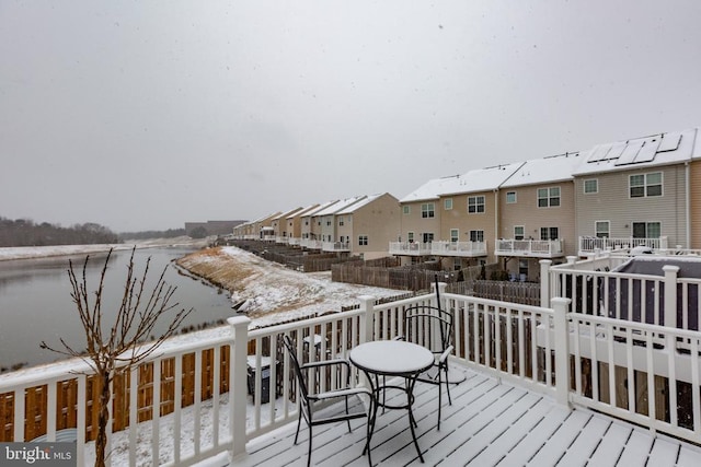 snow covered deck with a residential view and a water view