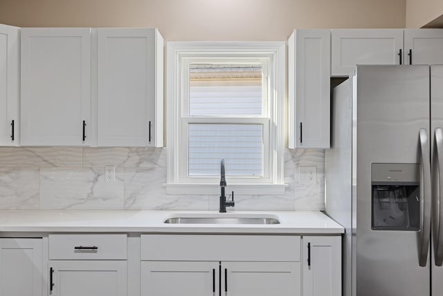 kitchen with sink, white cabinets, backsplash, and stainless steel fridge with ice dispenser