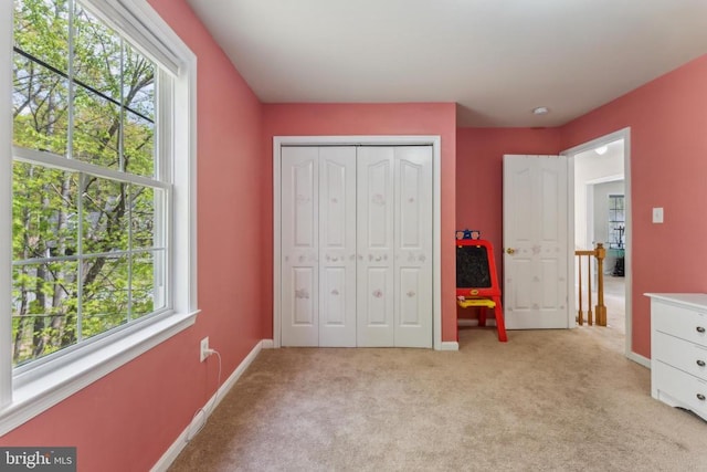 bedroom featuring baseboards, a closet, and light colored carpet