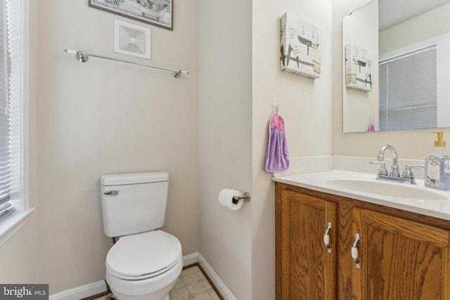 bathroom featuring toilet, vanity, and baseboards