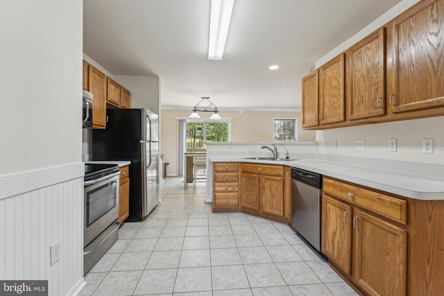 kitchen with stainless steel appliances, a peninsula, a sink, and brown cabinets