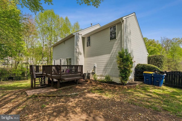 rear view of property with a wooden deck, cooling unit, and fence