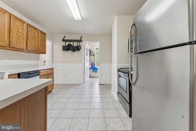 kitchen featuring brown cabinets, light tile patterned floors, appliances with stainless steel finishes, and light countertops