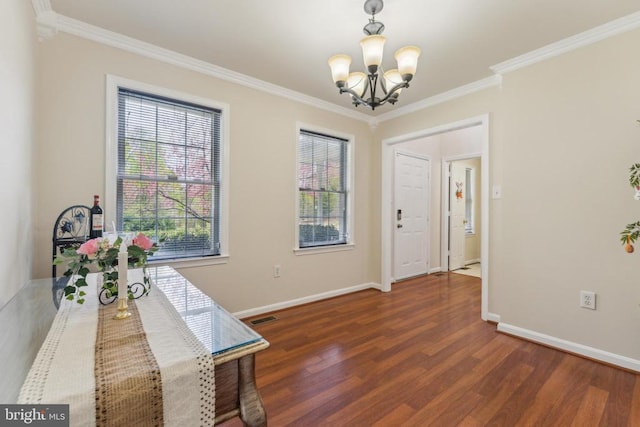 dining space with ornamental molding, a notable chandelier, wood finished floors, and plenty of natural light