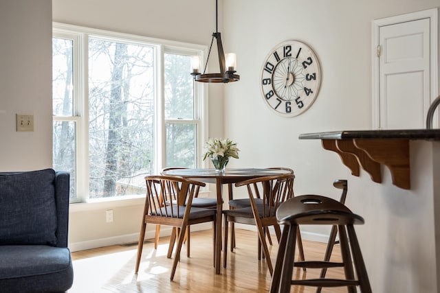 dining space with an inviting chandelier, light wood-style floors, visible vents, and baseboards