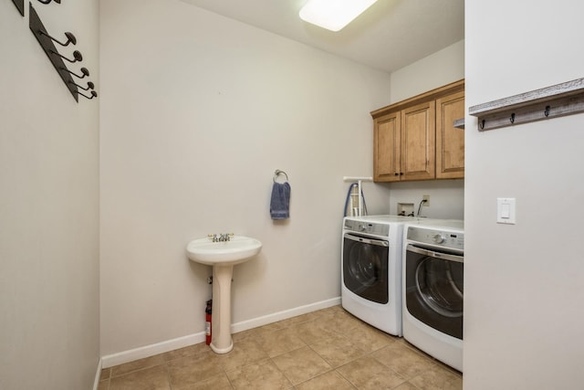 laundry room featuring light tile patterned floors, baseboards, washing machine and clothes dryer, cabinet space, and a sink