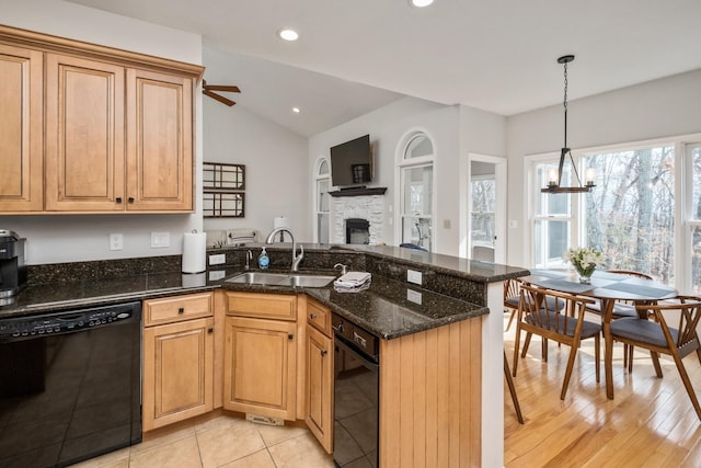 kitchen featuring dishwasher, vaulted ceiling, a stone fireplace, a peninsula, and a sink