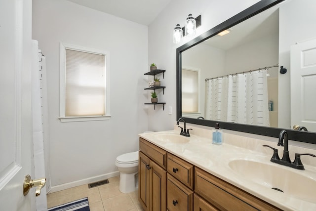 bathroom with a sink, toilet, double vanity, and tile patterned floors